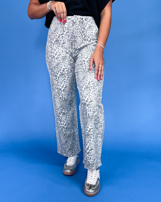 Person wearing white pants with black pattern against a blue background