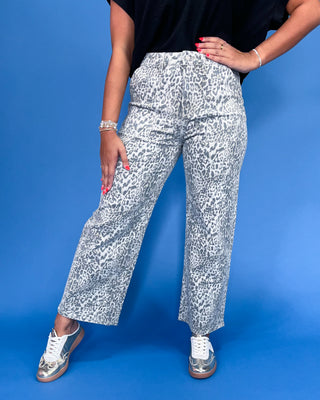 Person wearing white pants with black pattern against a blue background