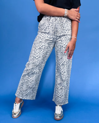 Person wearing white pants with black pattern against a blue background