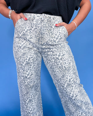 Person wearing white pants with gray leopard print against a blue background