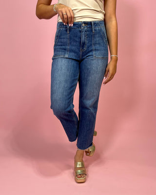 Person wearing blue jeans on a pink background