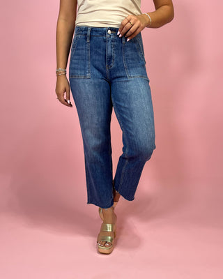 Person wearing blue jeans on a pink background