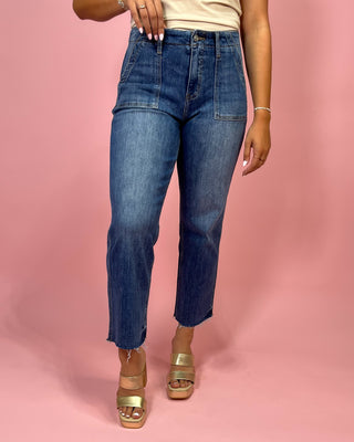 Person wearing blue jeans on a pink background
