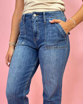 Person wearing blue jeans on a pink background