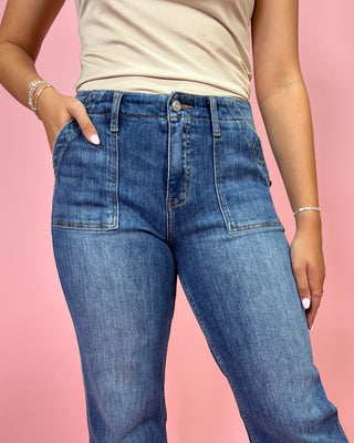 Person wearing blue jeans and a beige top on a pink background