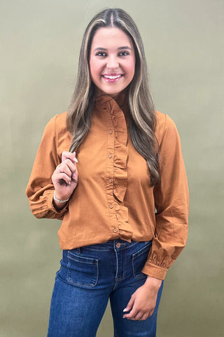 Woman wearing a brown shirt and blue jeans against a green background