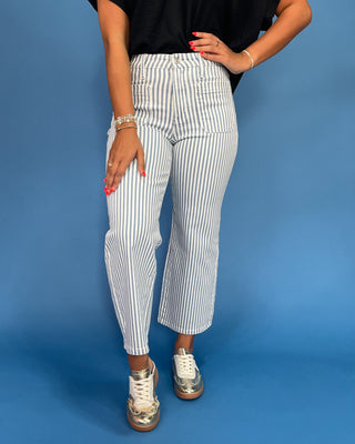 Person wearing white and black striped pants on a blue background