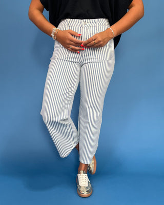Person wearing black top and white striped pants on a blue background
