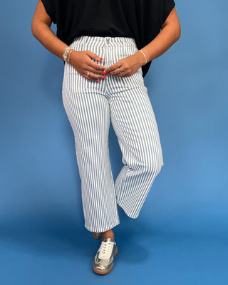 Person wearing white and blue striped pants against a blue background