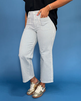 Person wearing white striped pants with a blue background
