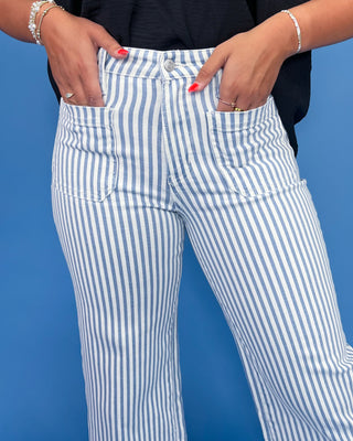 White and blue striped pants worn by a person against a blue background