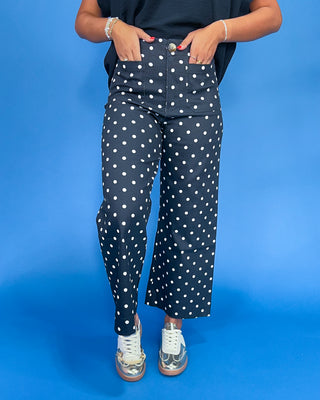 Person wearing navy blue pants with white polka dots on a blue background