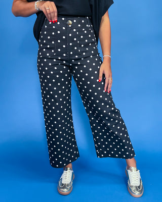 Person wearing navy blue pants with white polka dots on a blue background