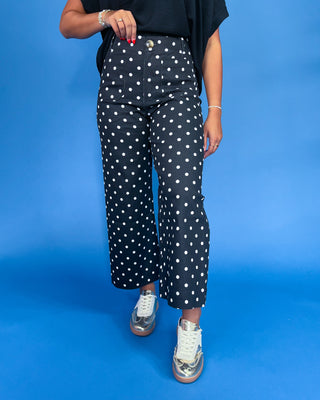 Person wearing black polka dot pants on a blue background