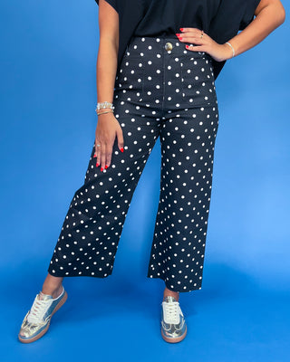 Person wearing navy blue pants with white polka dots against a blue background