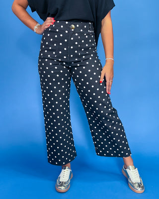Person wearing navy blue pants with white polka dots on a blue background