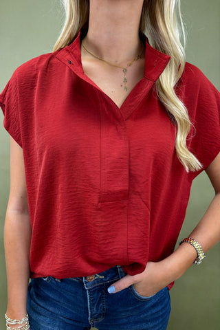 Person wearing a red sleeveless top with a plain background