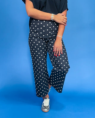 Person wearing navy pants with white polka dots on a blue background
