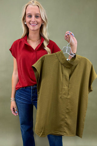 Woman holding a green shirt on a hanger against a plain background