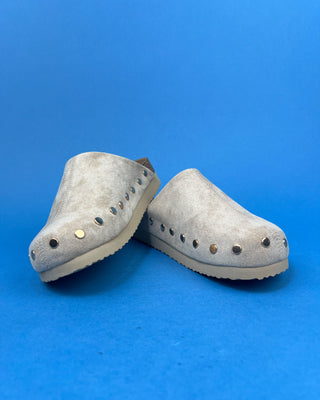 Nude suede-look slip-on clog mules featuring metallic round studs, closed rounded toes, and cork-look footbeds.