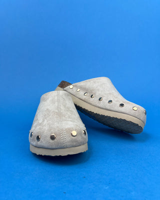 Nude suede-look slip-on clog mules featuring metallic round studs, closed rounded toes, and cork-look footbeds.