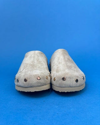 Nude suede-look slip-on clog mules featuring metallic round studs, closed rounded toes, and cork-look footbeds.