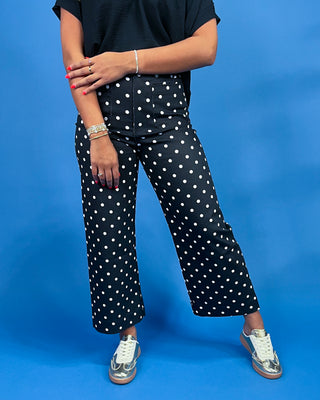 Person wearing black pants with white polka dots on a blue background