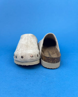 Nude suede-look slip-on clog mules featuring metallic round studs, closed rounded toes, and cork-look footbeds.
