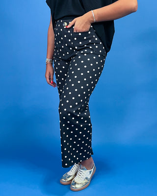 Person wearing black pants with white polka dots against a blue background