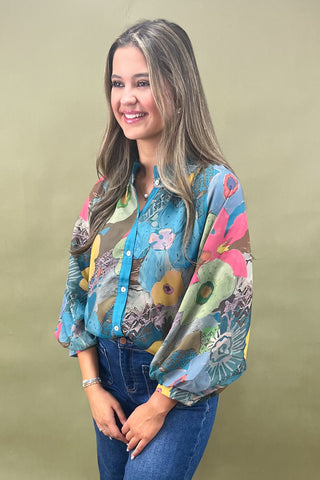 Woman wearing a colorful floral blouse against a beige background