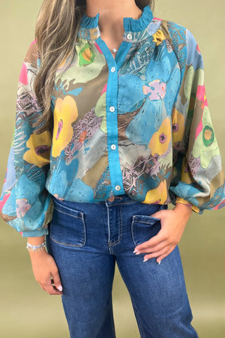 Person wearing a colorful patterned shirt with blue jeans on a beige background