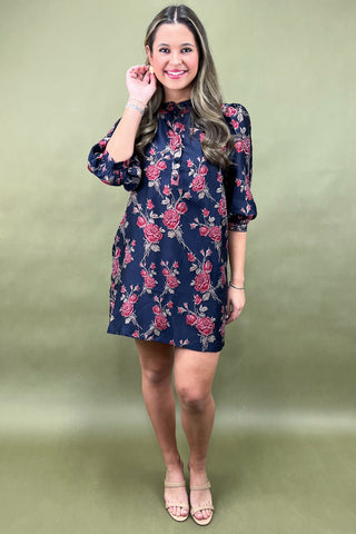 Woman wearing a navy floral dress against a green background