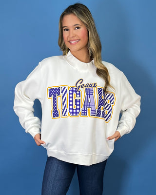 White Geaux Tigers graphic sweatshirt with bold purple mixed-print lettering, gold accents, mock neckline, long sleeves, and a relaxed fit.