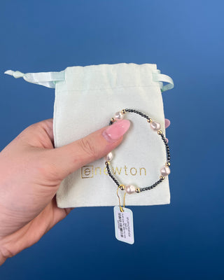Shop the Purpose Admire Pearl 8mm Hematite Bracelet by enewton, featuring dark hematite beads, white pearl accents, and elegant gold-tone details.