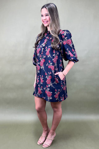 Woman wearing a floral dress against a plain background