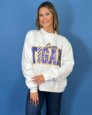 White Geaux Tigers graphic sweatshirt with bold purple mixed-print lettering, gold accents, mock neckline, long sleeves, and a relaxed fit.