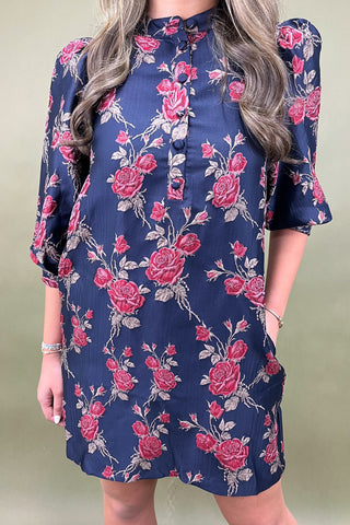 Navy dress with pink floral pattern worn by a person against a plain background