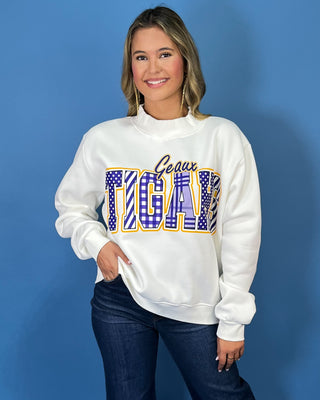 White Geaux Tigers graphic sweatshirt with bold purple mixed-print lettering, gold accents, mock neckline, long sleeves, and a relaxed fit.