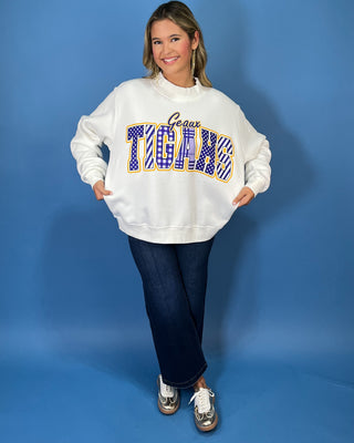White Geaux Tigers graphic sweatshirt with bold purple mixed-print lettering, gold accents, mock neckline, long sleeves, and a relaxed fit.
