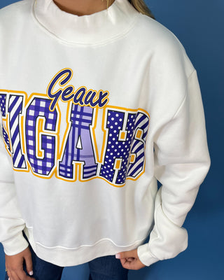 White Geaux Tigers graphic sweatshirt with bold purple mixed-print lettering, gold accents, mock neckline, long sleeves, and a relaxed fit.