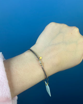 Shop the Hope Classic Signature Cross Moonlight Bracelet by enewton, featuring smoky gray beads and a delicate gold cross charm. Perfect for everyday wear.