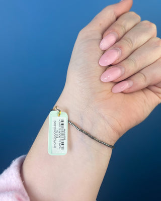 Shop the Hope Classic Signature Cross Moonlight Bracelet by enewton, featuring smoky gray beads and a delicate gold cross charm. Perfect for everyday wear.