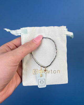 Shop the Hope Classic Signature Cross Moonlight Bracelet by enewton, featuring smoky gray beads and a delicate gold cross charm. Perfect for everyday wear.