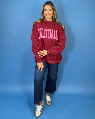 Burgundy Dilly Dally graphic sweatshirt with bold pink lettering, mock neckline, long sleeves, ribbed trim, and a relaxed oversized fit.