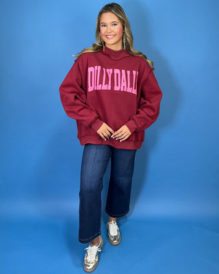 Burgundy Dilly Dally graphic sweatshirt with bold pink lettering, mock neckline, long sleeves, ribbed trim, and a relaxed oversized fit.
