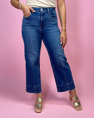 Person wearing blue jeans on a pink background