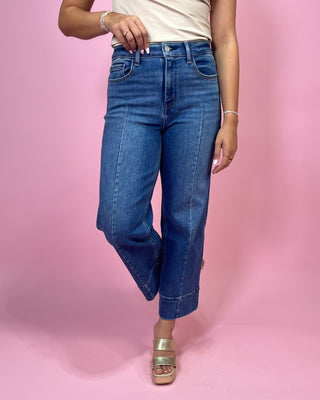 Person wearing blue jeans on a pink background