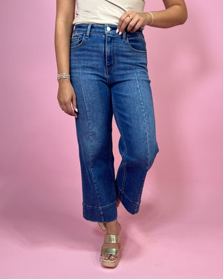 Person wearing blue jeans on a pink background