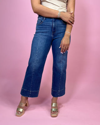 Person wearing blue jeans on a pink background
