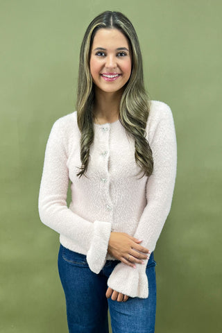 Woman wearing a white sweater and blue jeans against a green background